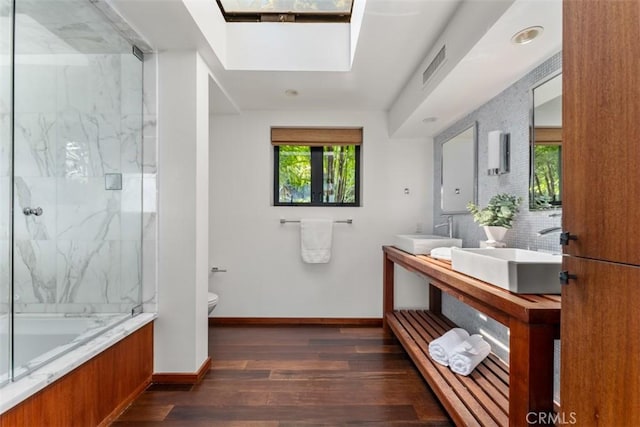 bathroom with toilet, vanity, hardwood / wood-style floors, decorative backsplash, and a shower with shower door