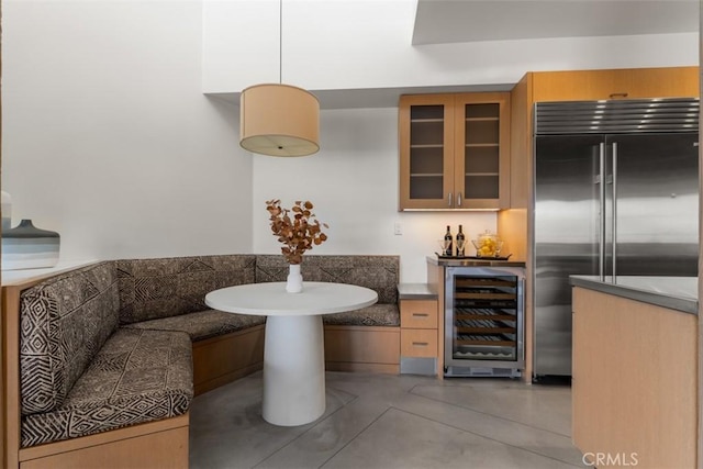 kitchen featuring breakfast area, light brown cabinets, wine cooler, built in fridge, and hanging light fixtures