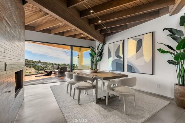 dining space with wooden ceiling, a large fireplace, and beamed ceiling