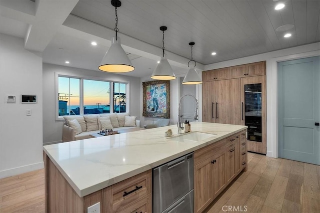 kitchen featuring dishwasher, a center island with sink, pendant lighting, sink, and light stone countertops