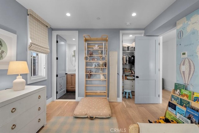 bedroom featuring light wood-type flooring, a closet, ensuite bathroom, and a walk in closet