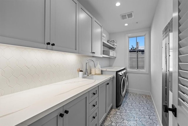 laundry room with washer and clothes dryer, sink, light tile patterned floors, and cabinets