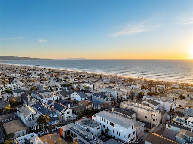 aerial view at dusk featuring a water view and a view of the beach