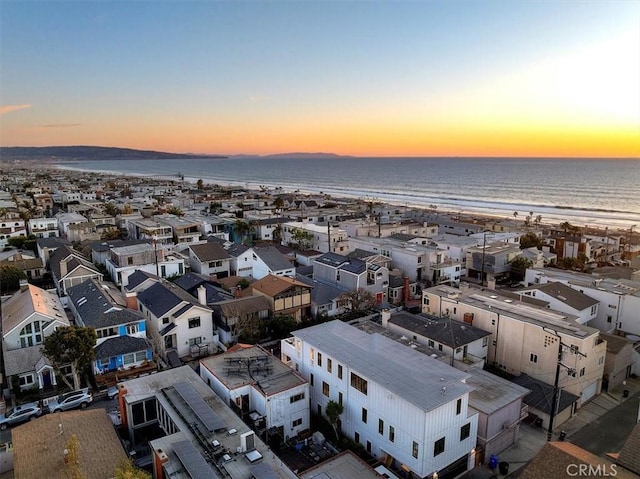 aerial view at dusk with a beach view and a water view