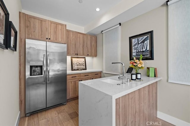 kitchen featuring light hardwood / wood-style floors, sink, stainless steel fridge with ice dispenser, and kitchen peninsula