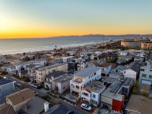 aerial view at dusk featuring a beach view and a water view