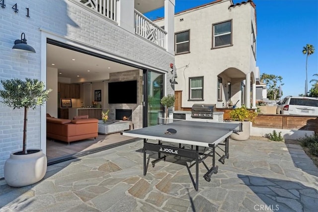 view of patio featuring an outdoor kitchen, a balcony, exterior fireplace, and area for grilling