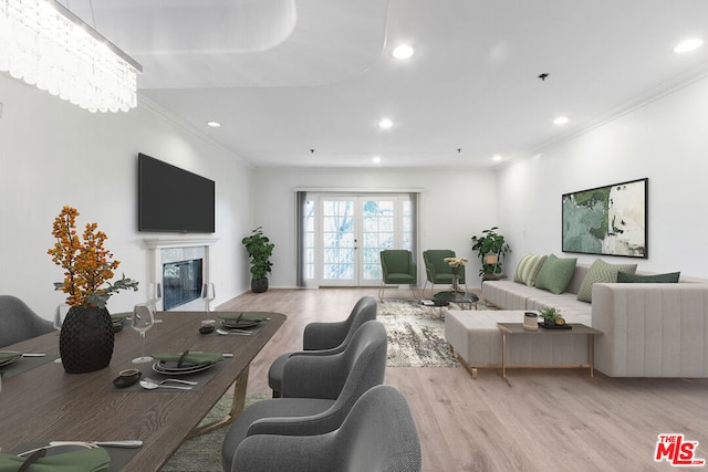 living room with light hardwood / wood-style floors, ornamental molding, and a notable chandelier