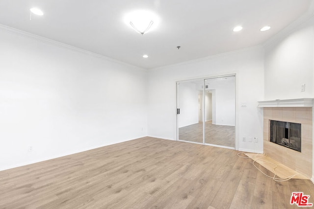 unfurnished living room with ornamental molding, light hardwood / wood-style floors, and a tiled fireplace