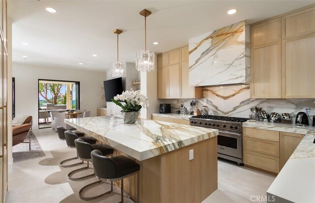 kitchen with tasteful backsplash, a kitchen island, high end stainless steel range oven, light brown cabinets, and custom range hood