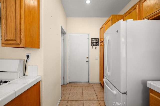 kitchen featuring tile countertops, white fridge, and light tile patterned flooring