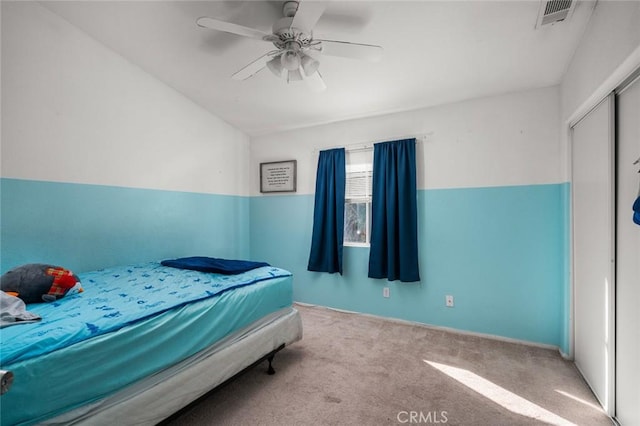 carpeted bedroom featuring ceiling fan and a closet