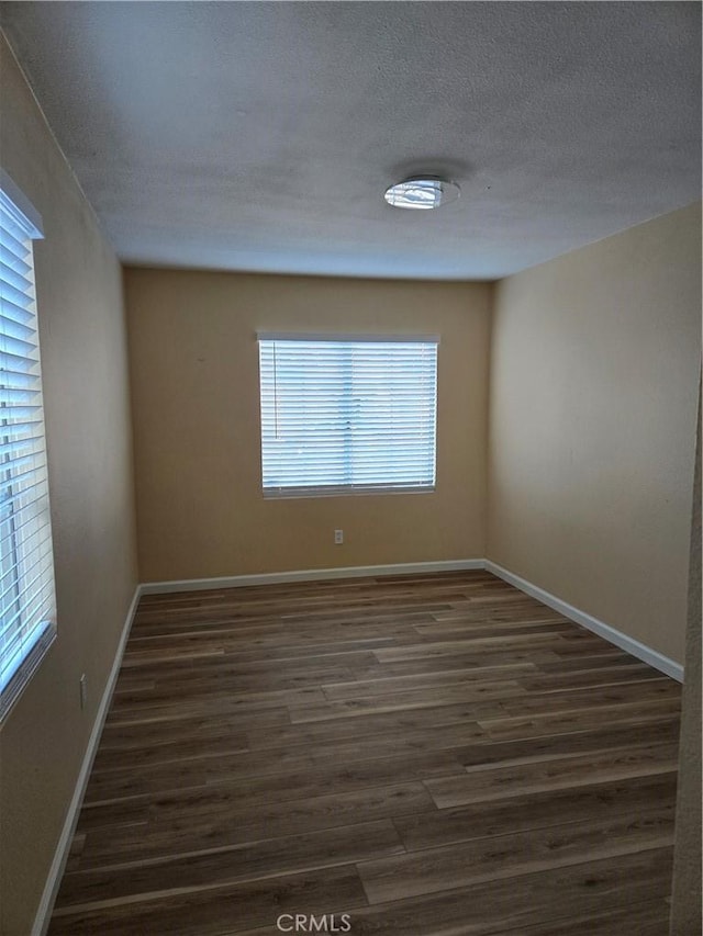 empty room with a textured ceiling and dark hardwood / wood-style floors