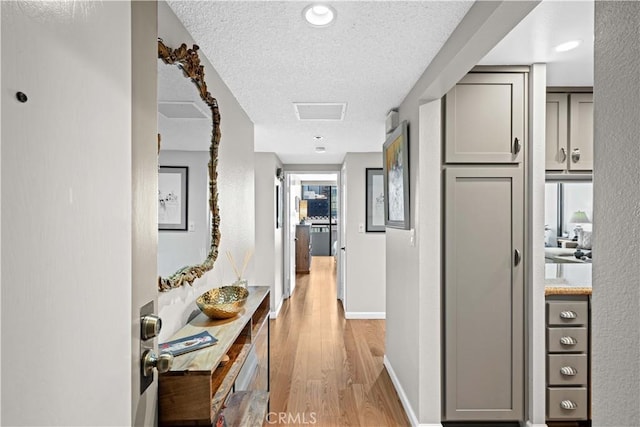 hallway with a textured ceiling and light hardwood / wood-style floors