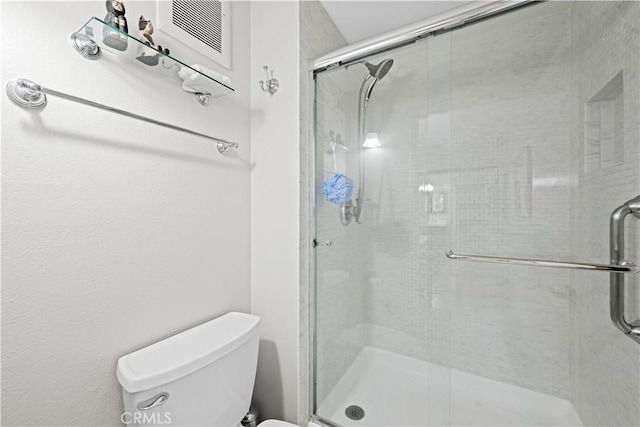 bathroom featuring toilet and a shower with door