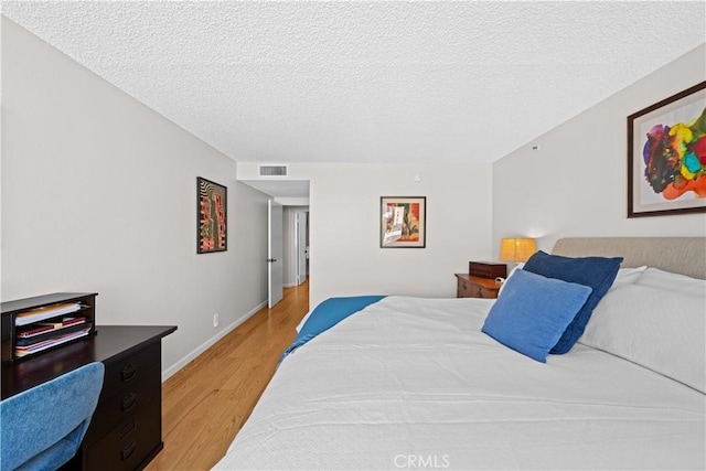 bedroom with a textured ceiling and light hardwood / wood-style floors