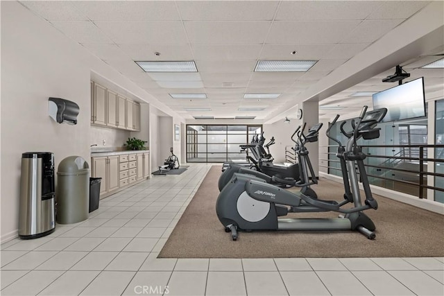 workout area featuring light tile patterned floors and a paneled ceiling