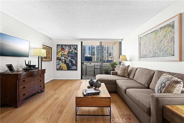 living room with a wall of windows, a textured ceiling, and light hardwood / wood-style floors