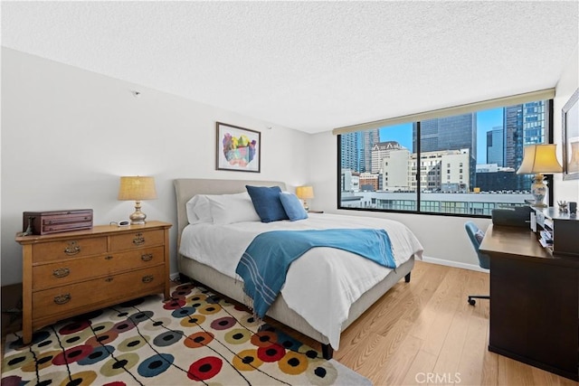 bedroom with a textured ceiling and light hardwood / wood-style floors