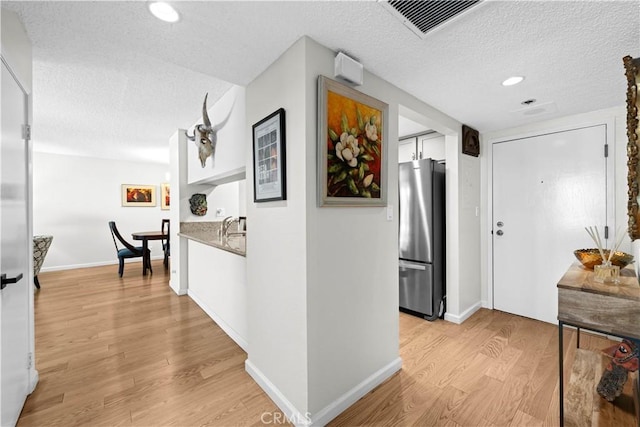 hall featuring a textured ceiling and light hardwood / wood-style floors