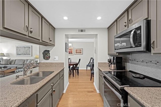 kitchen featuring stainless steel appliances, gray cabinetry, tasteful backsplash, light hardwood / wood-style flooring, and sink