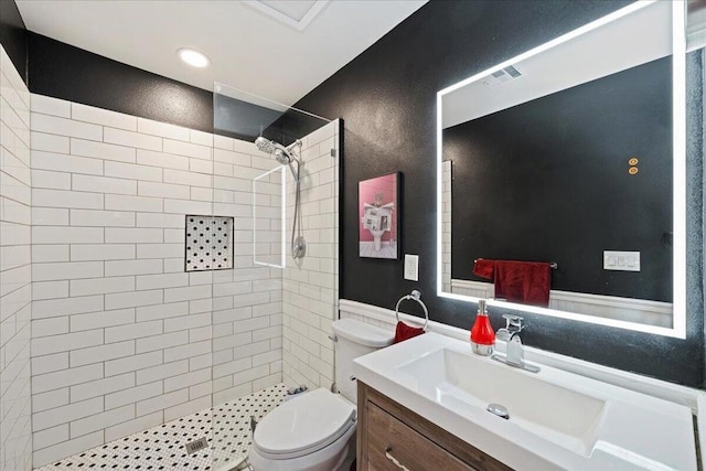 bathroom with tiled shower, vanity, and toilet