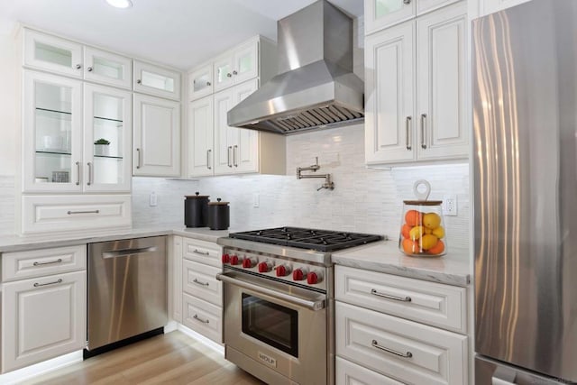 kitchen with extractor fan, stainless steel appliances, decorative backsplash, white cabinets, and light stone counters