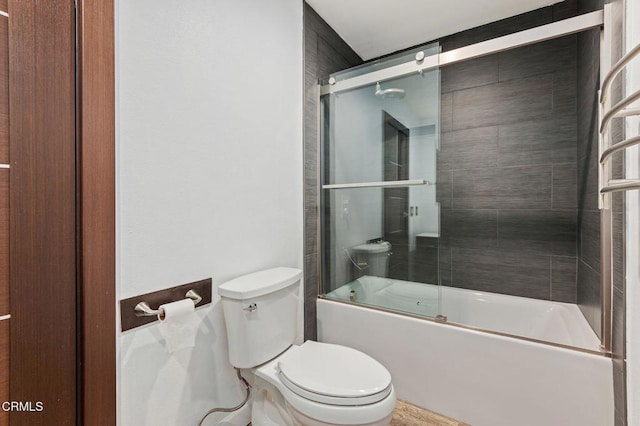 bathroom featuring toilet and shower / bath combination with glass door