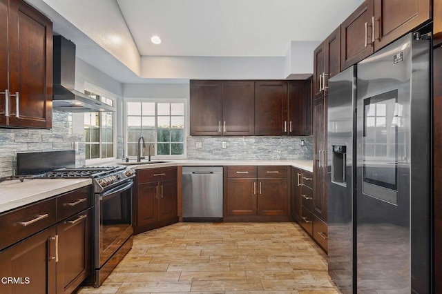 kitchen with appliances with stainless steel finishes, wall chimney range hood, sink, backsplash, and dark brown cabinets