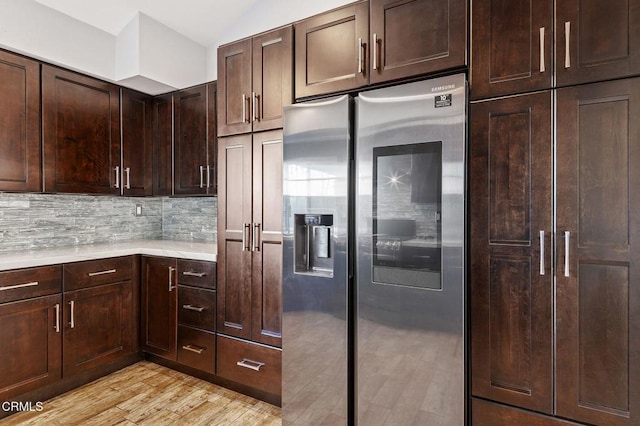 kitchen featuring backsplash, stainless steel fridge, dark brown cabinetry, and light hardwood / wood-style flooring