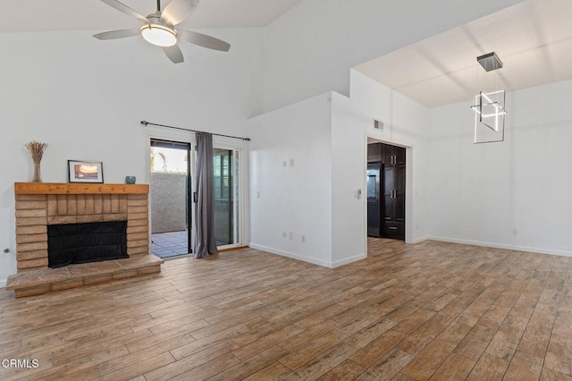 unfurnished living room with ceiling fan, wood-type flooring, a towering ceiling, and a fireplace