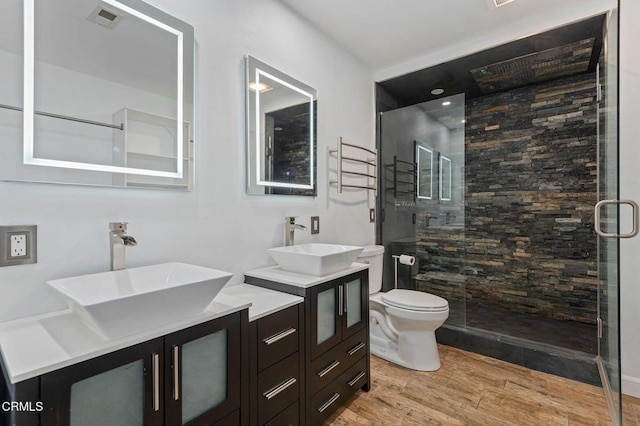 bathroom with toilet, a shower with door, and vanity