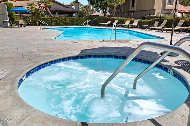 view of pool with a hot tub and a patio