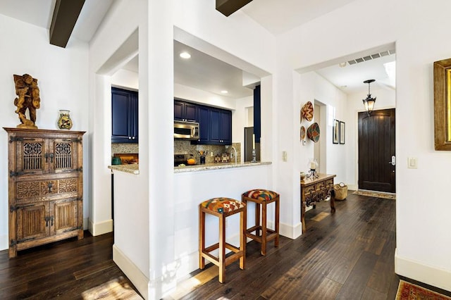 kitchen with kitchen peninsula, appliances with stainless steel finishes, backsplash, dark hardwood / wood-style flooring, and blue cabinets