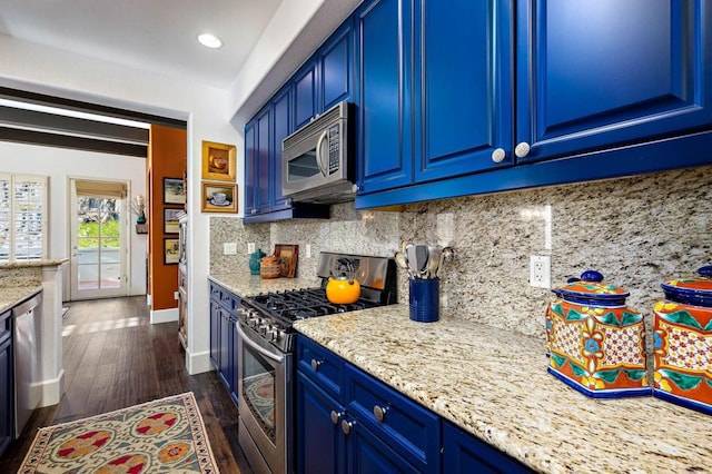 kitchen with appliances with stainless steel finishes, blue cabinets, tasteful backsplash, and light stone countertops