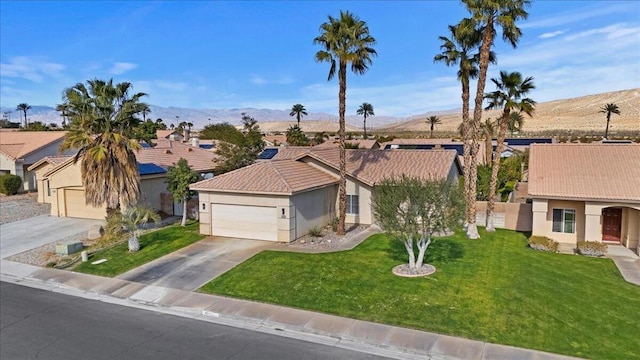 view of front facade featuring a garage, a front lawn, and a mountain view