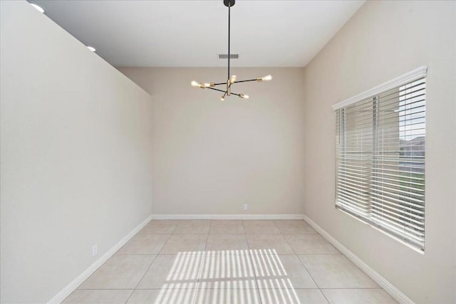 tiled empty room featuring an inviting chandelier