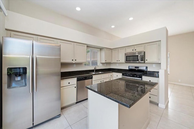 kitchen with light tile patterned flooring, appliances with stainless steel finishes, a center island, and dark stone counters