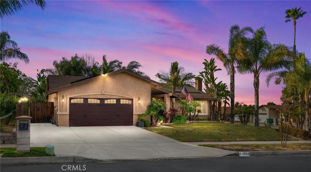 single story home featuring a lawn and a garage