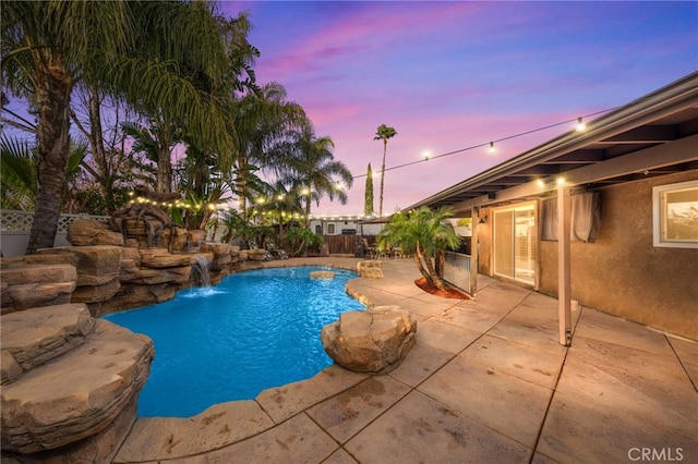 pool at dusk with pool water feature and a patio