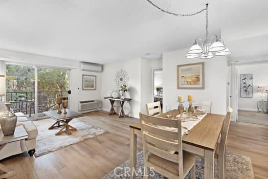 dining area featuring light wood-type flooring, a chandelier, and a wall mounted air conditioner