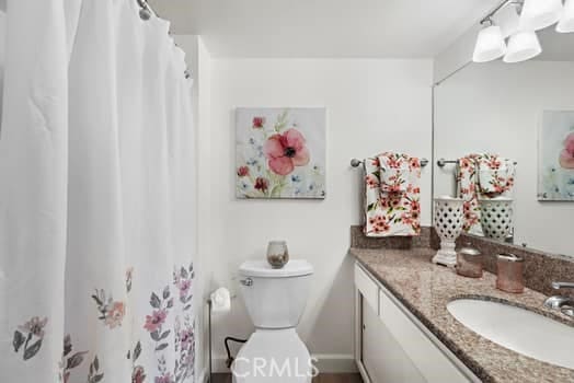 bathroom with curtained shower, toilet, and vanity