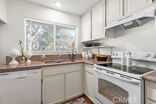 kitchen featuring white cabinetry, sink, and white appliances