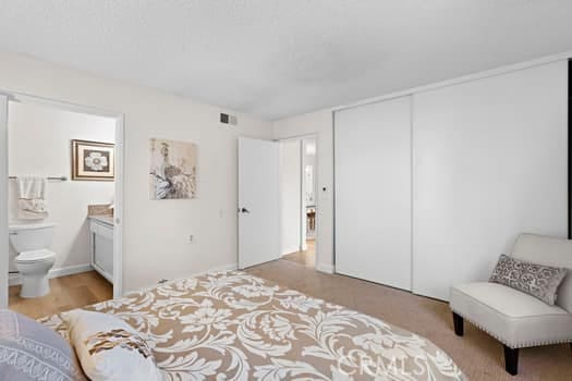 bedroom featuring a closet, ensuite bath, and light hardwood / wood-style flooring