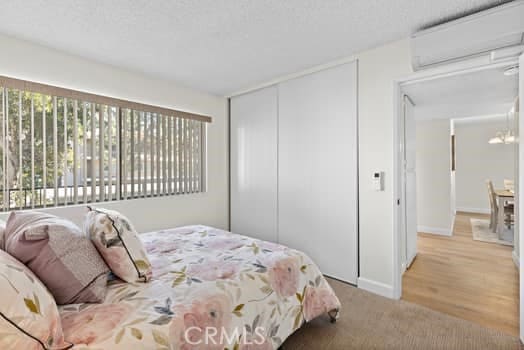 bedroom with a wall unit AC, a closet, and multiple windows