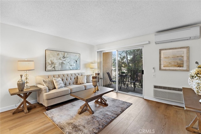 living room with a textured ceiling, light hardwood / wood-style floors, and a wall mounted air conditioner