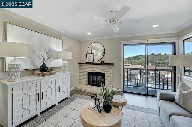 living room featuring ceiling fan, light tile patterned floors, a brick fireplace, and crown molding