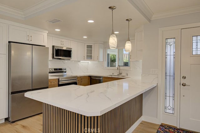 kitchen with kitchen peninsula, stainless steel appliances, decorative light fixtures, white cabinets, and sink