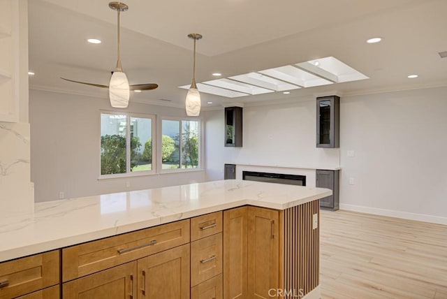 kitchen with light stone counters, hanging light fixtures, crown molding, and a fireplace