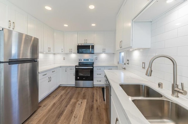 kitchen featuring white cabinets, dark hardwood / wood-style flooring, stainless steel appliances, sink, and light stone counters